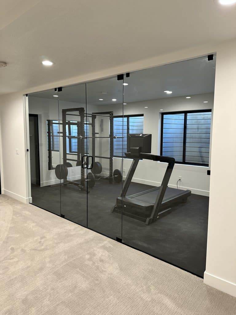 A modern gym featuring a glass wall and a treadmill, showcasing Creative Construction Solutions' innovative design.