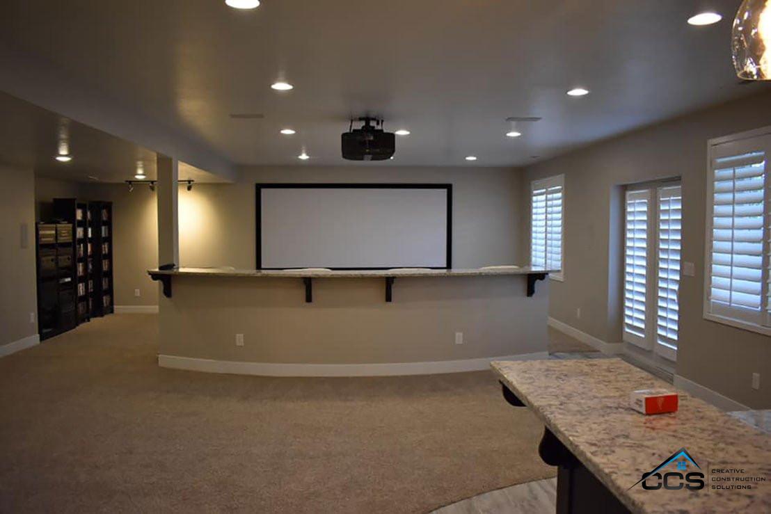 An image of a Utah finished basement theater room. A logo for CCS Creative Construction Solutions of Utah is in the bottom right-hand corner.