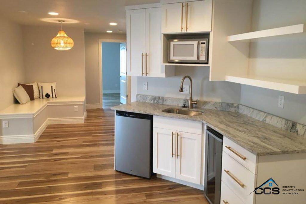 A modern kitchen featuring white cabinets and a sleek sink, showcasing Creative Construction Solutions' design expertise.
