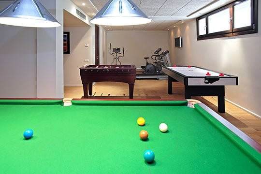 A vibrant game room featuring a pool table and two ping pong tables, designed by Creative Construction Solutions.