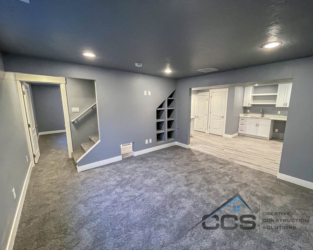 A finished basement in Utah. A clean grey palette throughout. A logo for CCS Creative Construction Solutions is in the bottom right-hand corner.