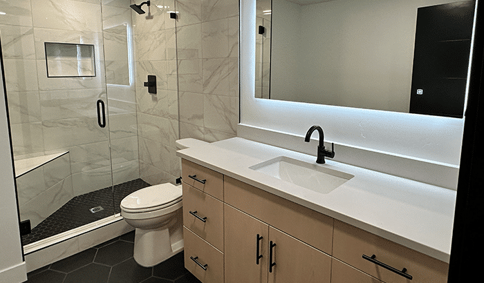 Renovated basement bathroom with shower, sink, and toilet.