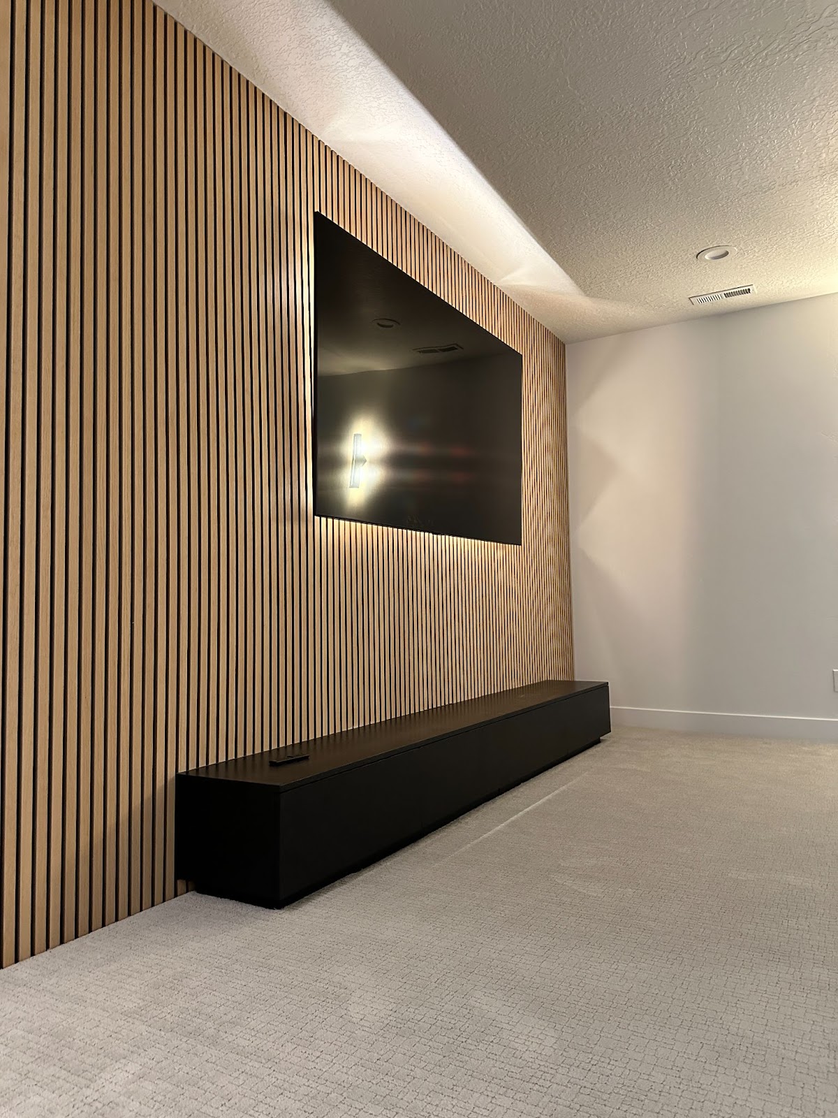An exquisite basement theater featuring a spacious living room with a sleek wall-mounted TV