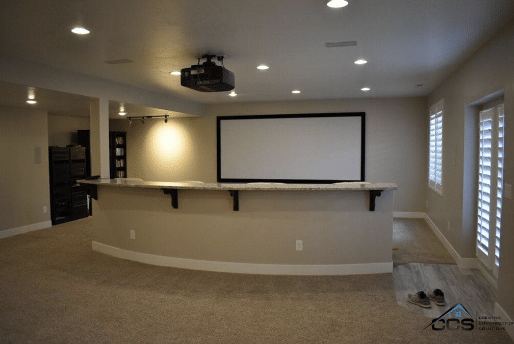 Spacious basement theater with projector screen and bar, perfect for a home cinema