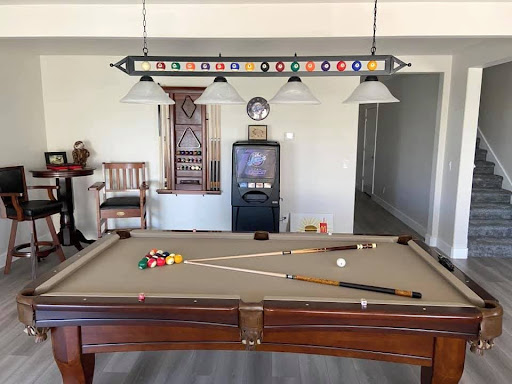 Stylish man cave with a pool table, bar seating, and decor in a finished basement.