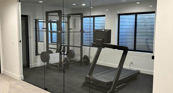A modern gym featuring a glass wall and a treadmill, showcasing Creative Construction Solutions' innovative design.